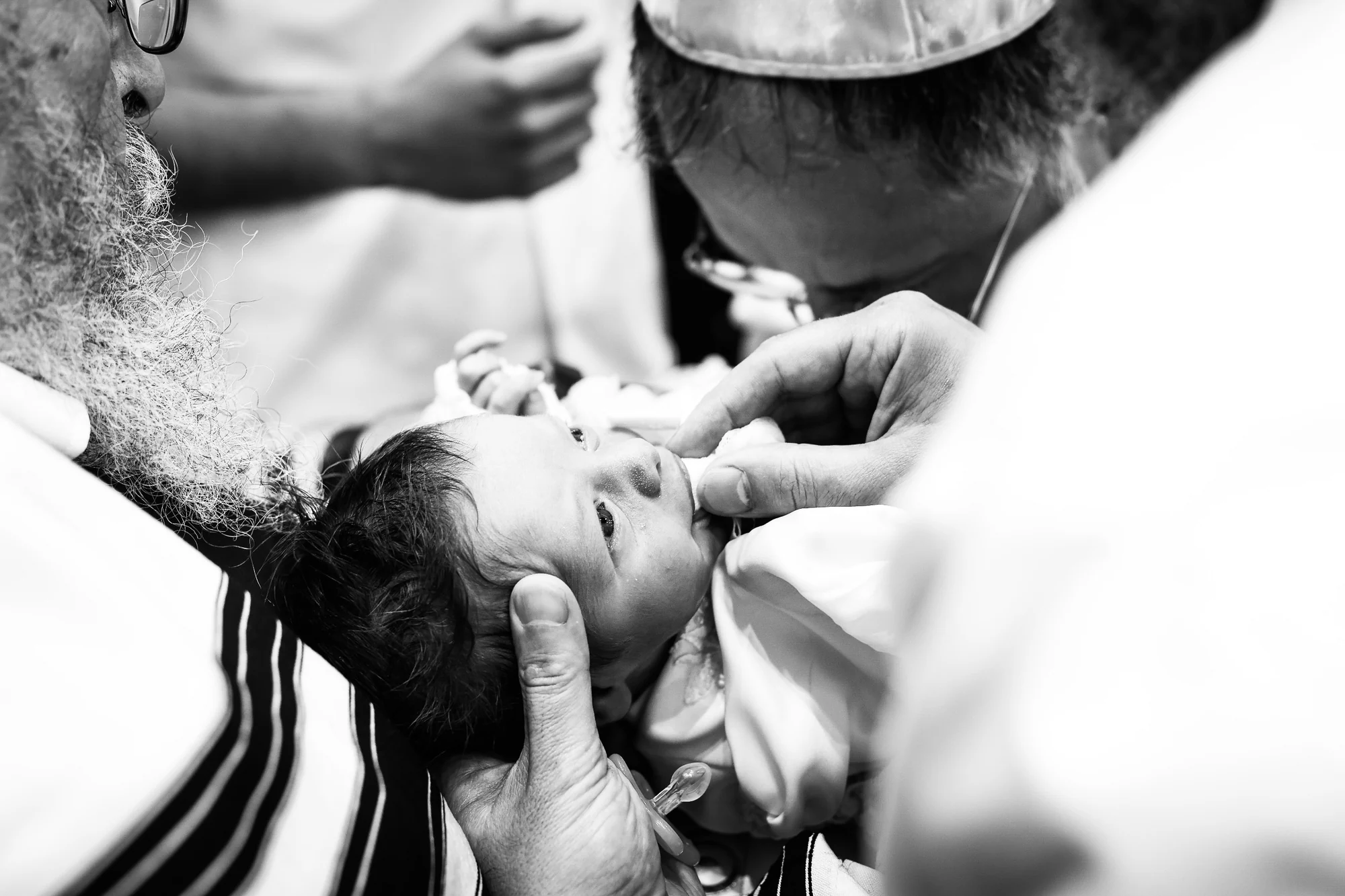 Le mohel et le sandak penchés sur bébé